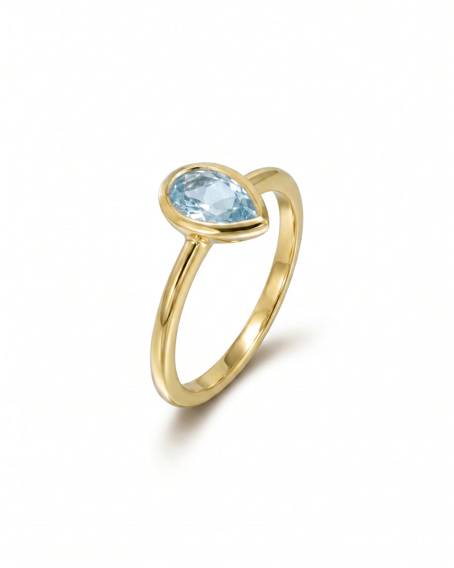 Gold ring with a bezel-set pear aquamarine solitaire.