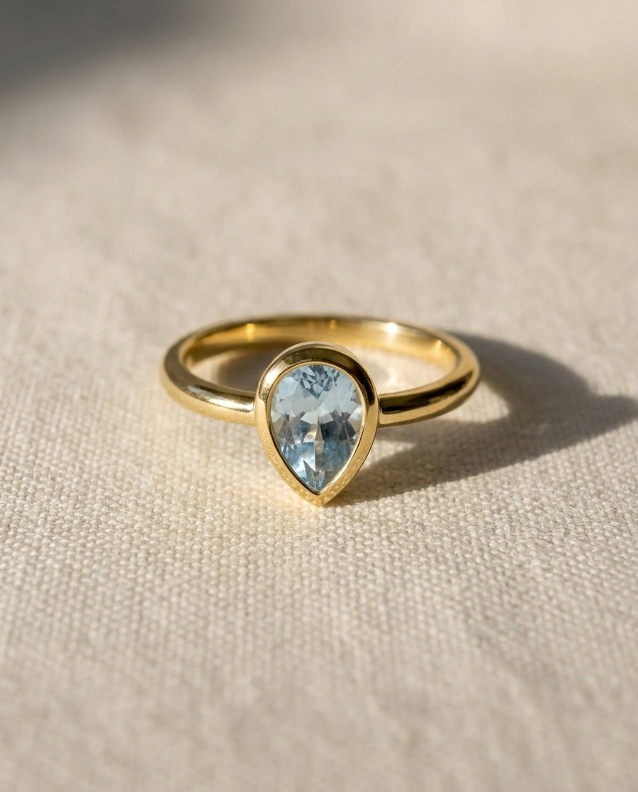 9ct yellow gold ring with a bezel-set pear aquamarine solitaire.