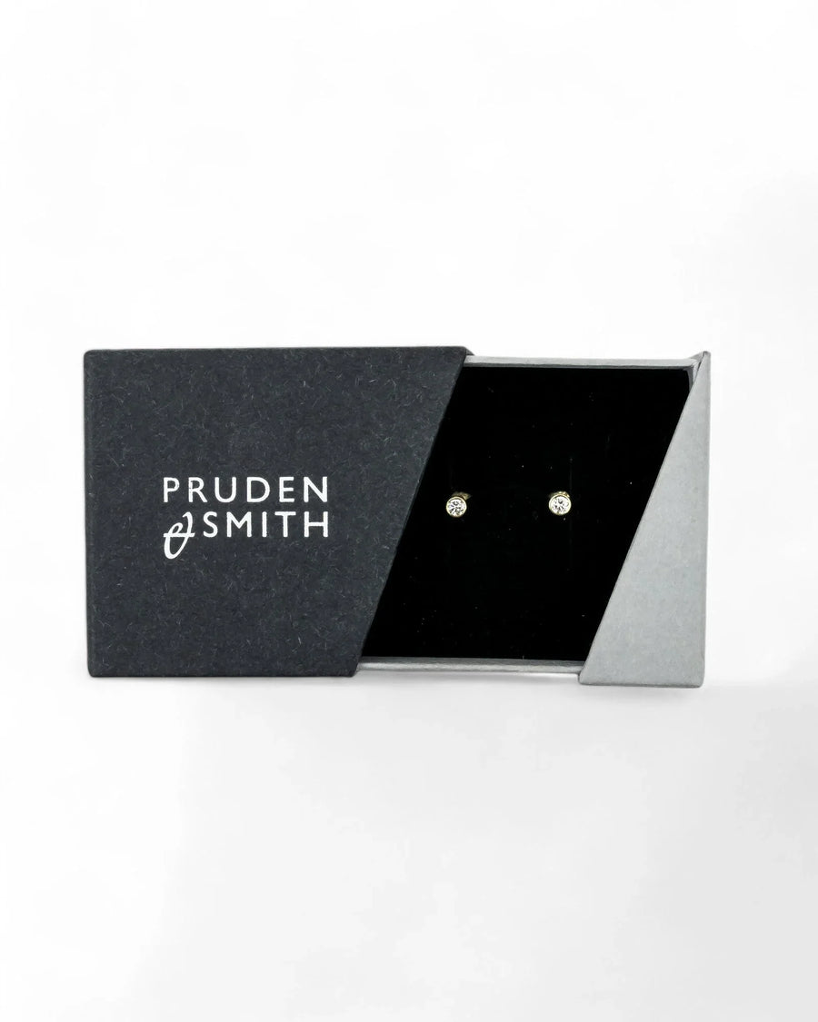 Gold bezel set diamond stud earrings in a black and gray box.