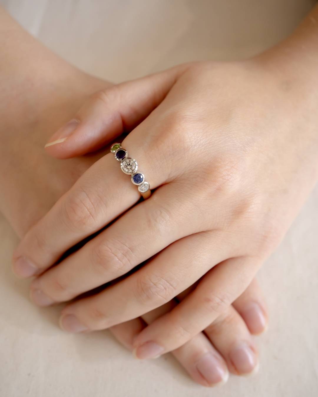 Hand wearing a unique gemstone and diamond ring with organic, modern design