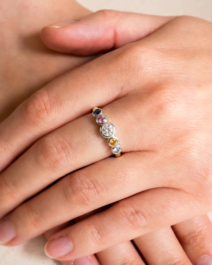 Gold and silver eternity ring with colorful birthstones and a central diamond.
