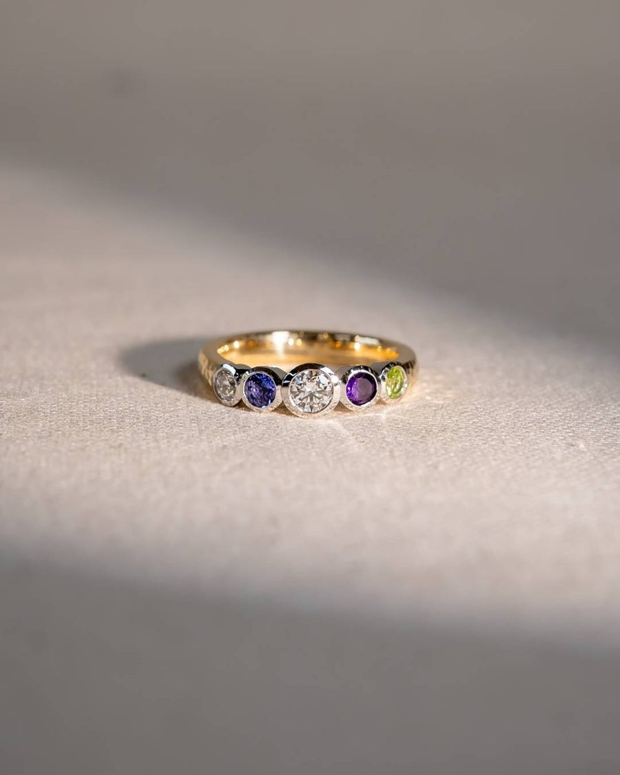 Gold eternity ring with round white, blue, purple, and green gemstones.