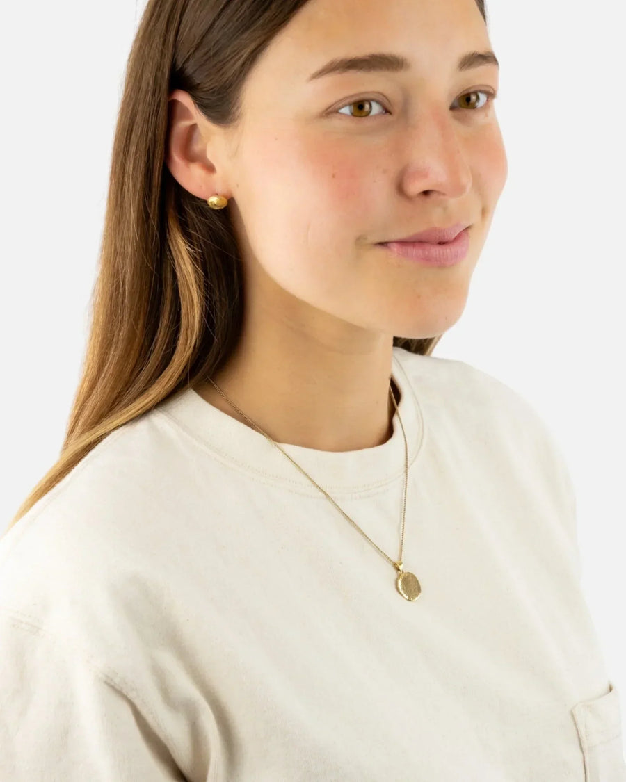 Woman wearing a hammered solid 9ct yellow gold coin pendant necklace and matching earring