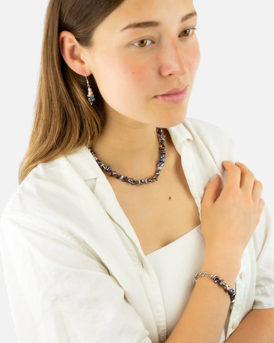 Woman wearing a black keshi pearl necklace, bracelet, and earrings set
