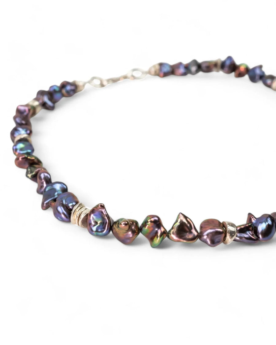Black keshi pearl necklace with organic shapes and gold spacers on white background