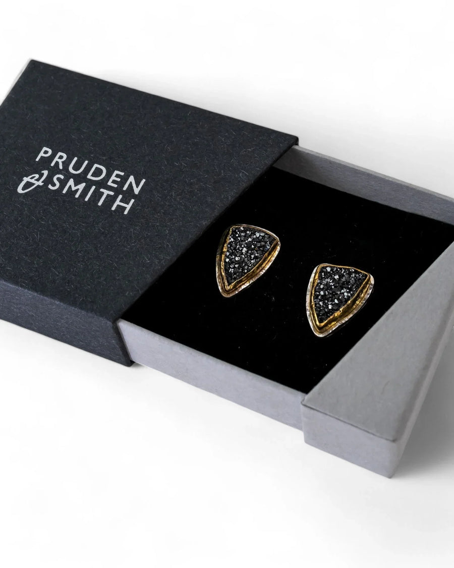 Black onyx druzy stud earrings with gold-toned edges in an open black box.