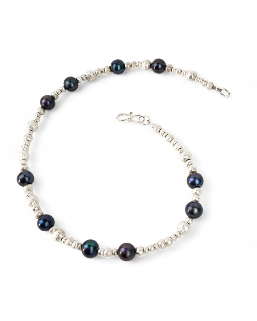 Black pearl and silver nugget beaded necklace on white background