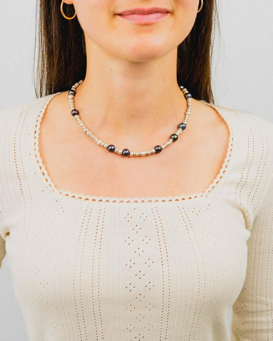 Woman wearing a black pearl and silver nugget beaded necklace with a cream knit top.
