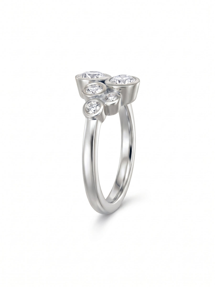 Silver ring featuring a cluster of five round diamonds in bezel settings on a smooth band.