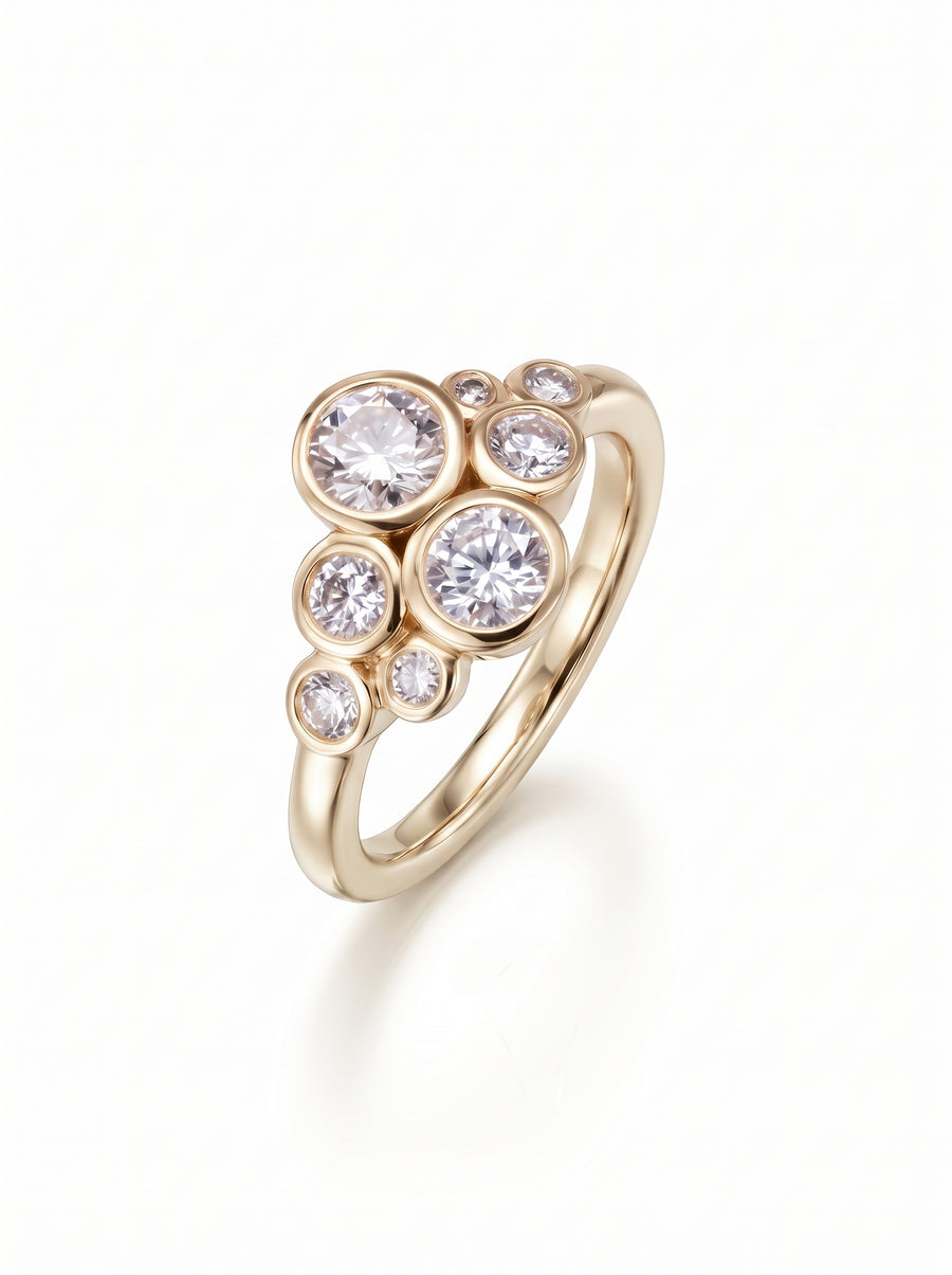 Gold ring featuring a cluster of round diamonds in bezel settings of varying sizes.