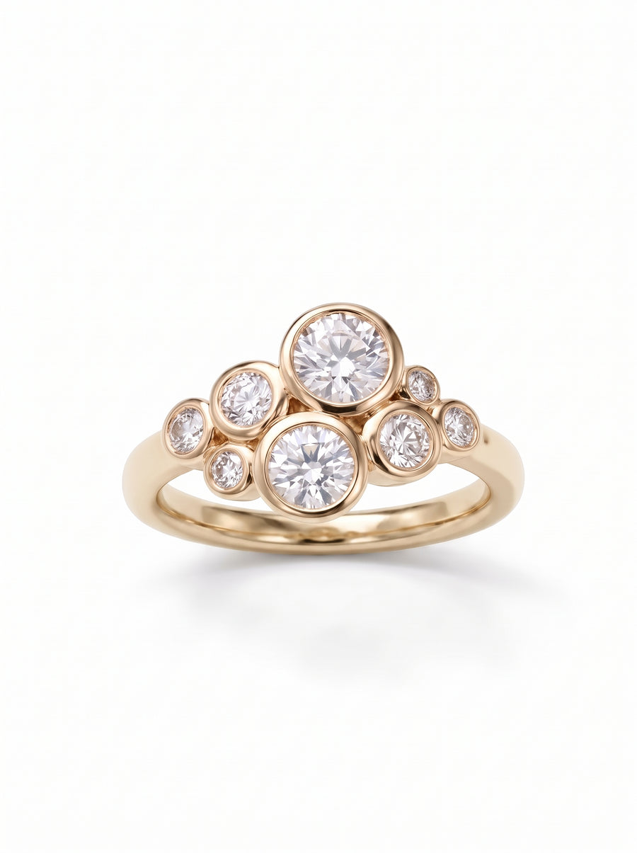 Gold ring featuring a cluster of round diamonds in bezel settings on a polished yellow gold band.