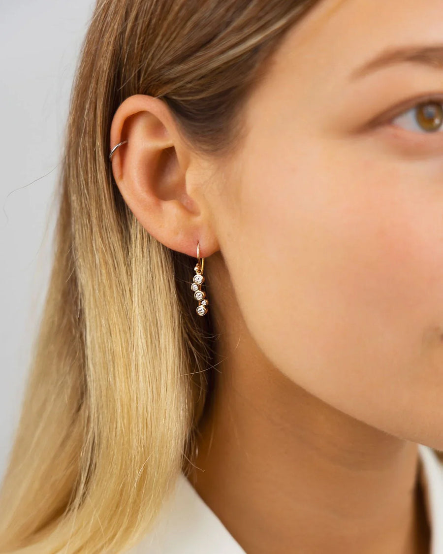 Gold drop earring with three round diamonds.