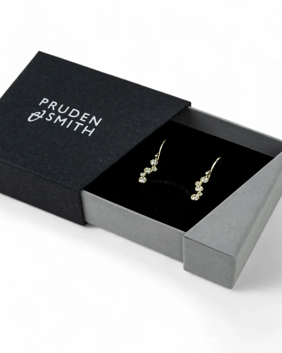 Gold drop earrings with four round diamonds in a black gift box.