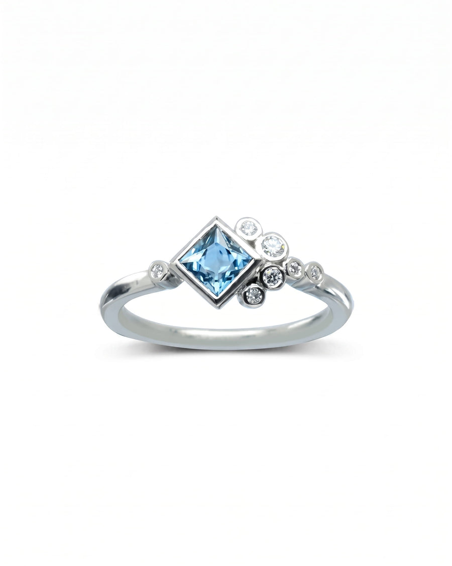 Silver ring with a square blue gemstone and round diamond accents.