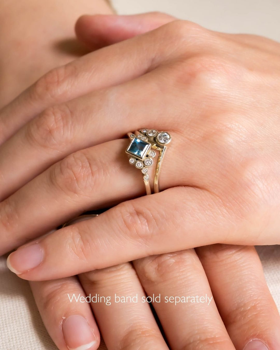 Gold engagement ring with a blue gemstone and diamonds.