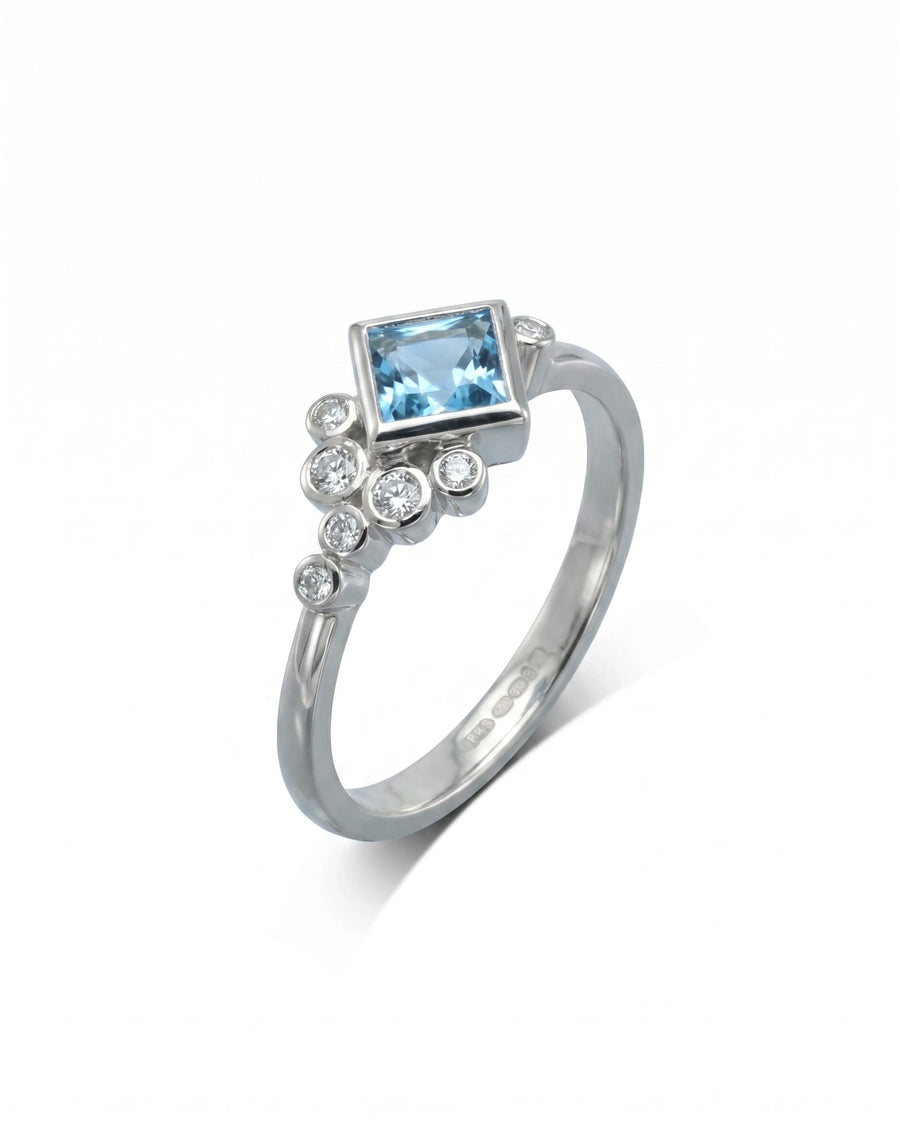 Silver ring with a square blue gemstone and round diamonds.