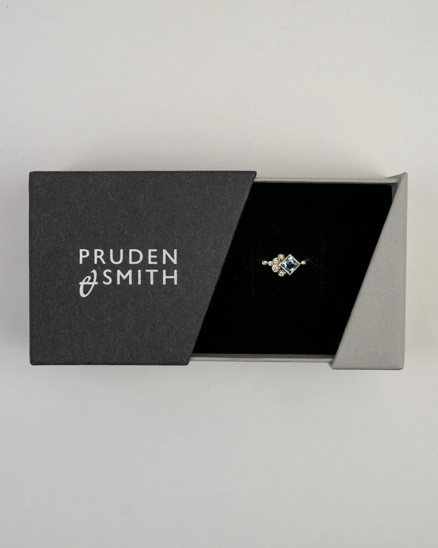 Silver ring with a square blue gemstone and small diamonds in a black box.