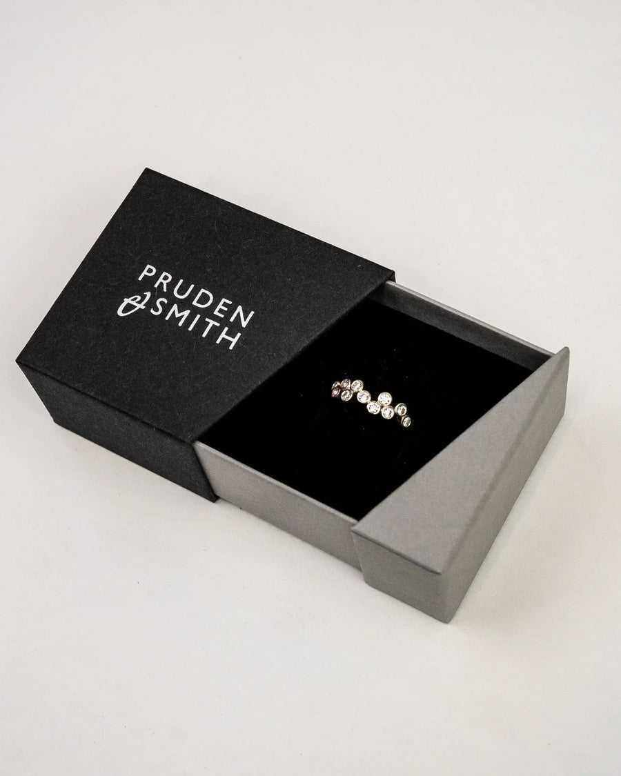 Gold ring with multiple round diamonds in a black and gray box.