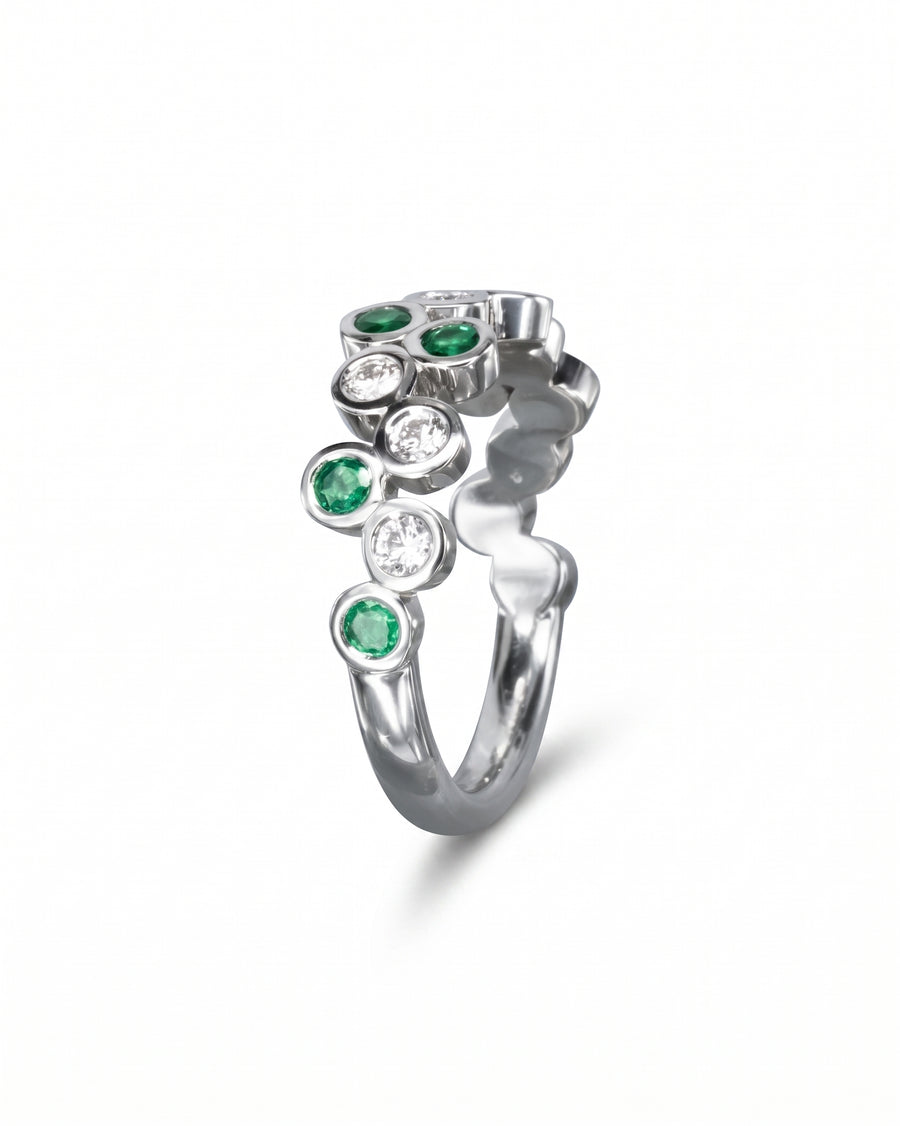 Silver half eternity ring with alternating round emeralds and diamonds in a bubble design.