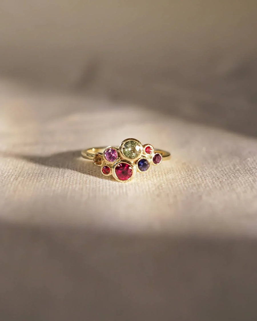 Gold ring with a cluster of multi-coloured sapphire gemstones.