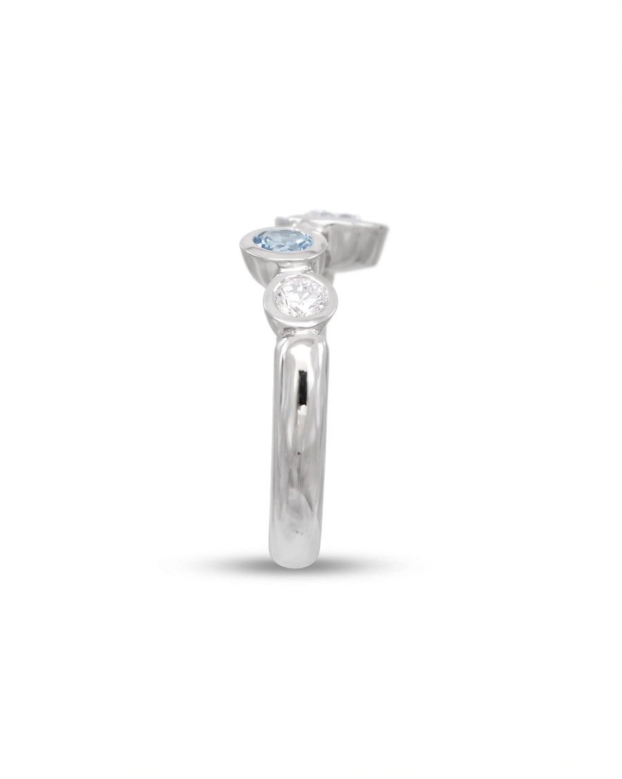 Silver ring with offset aquamarine and diamond gemstones.
