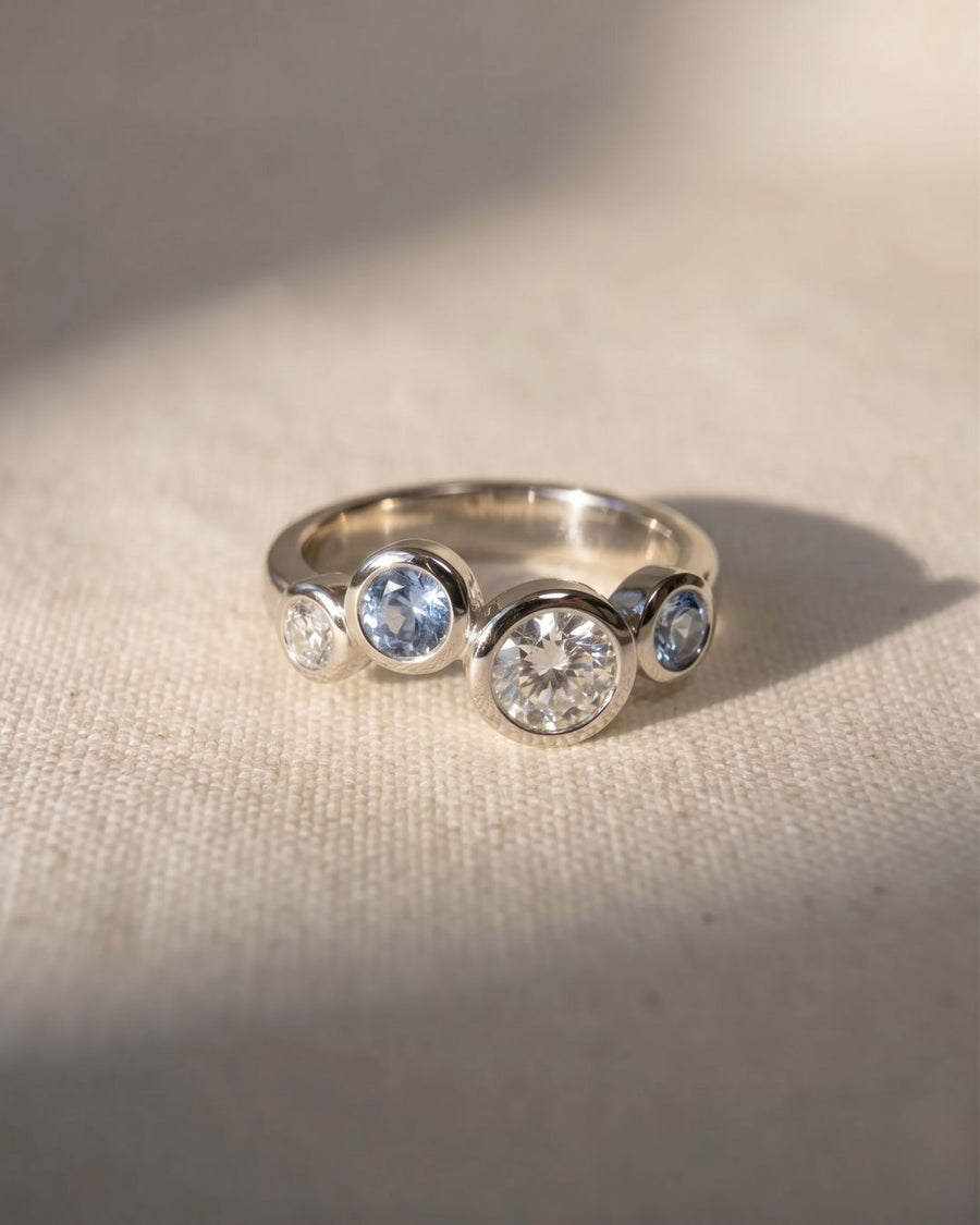Platinum ring with offset aquamarine and diamond gemstones.