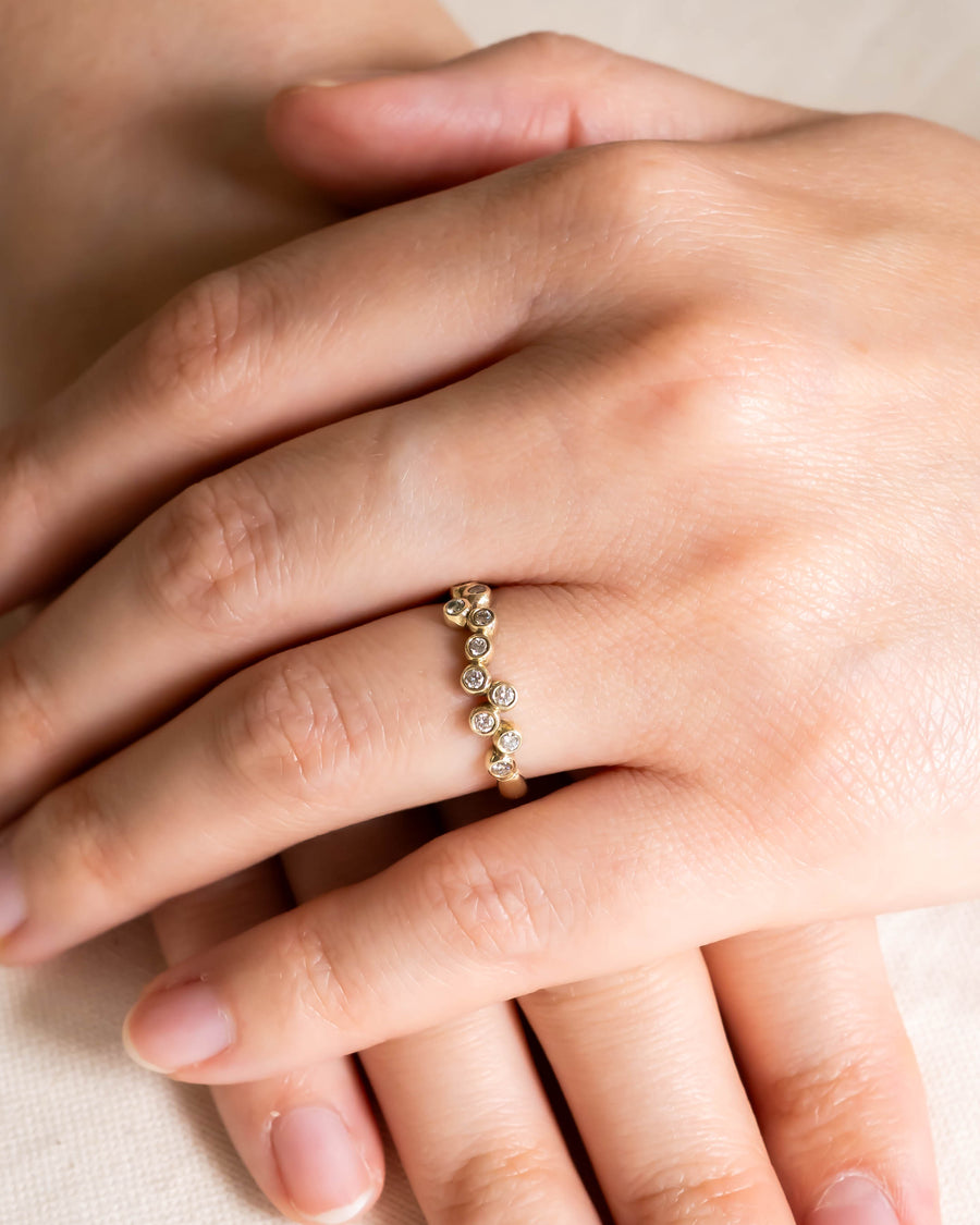 Gold offset diamond eternity ring on a hand.