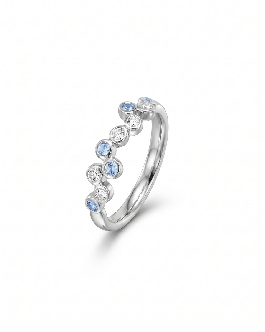 Silver half eternity ring with offset blue gemstones and diamonds.