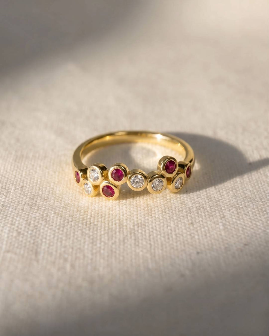 Gold half eternity ring with offset ruby and diamond gemstones.