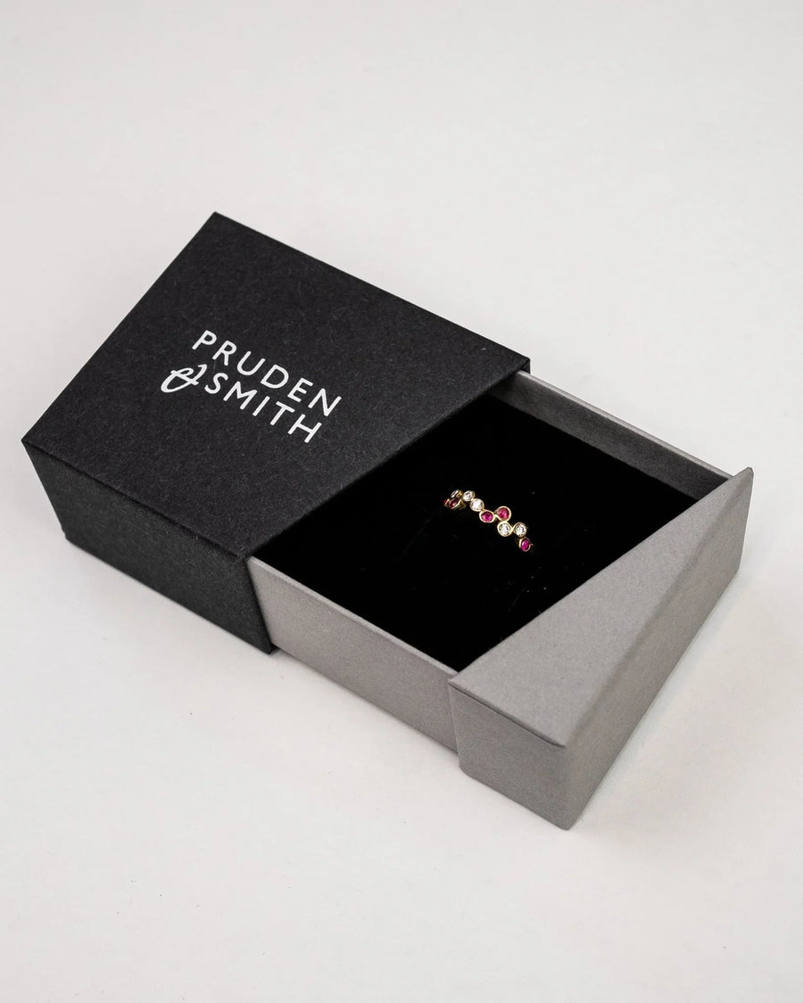 Gold offset gemstone diamond half eternity ring in a black box.