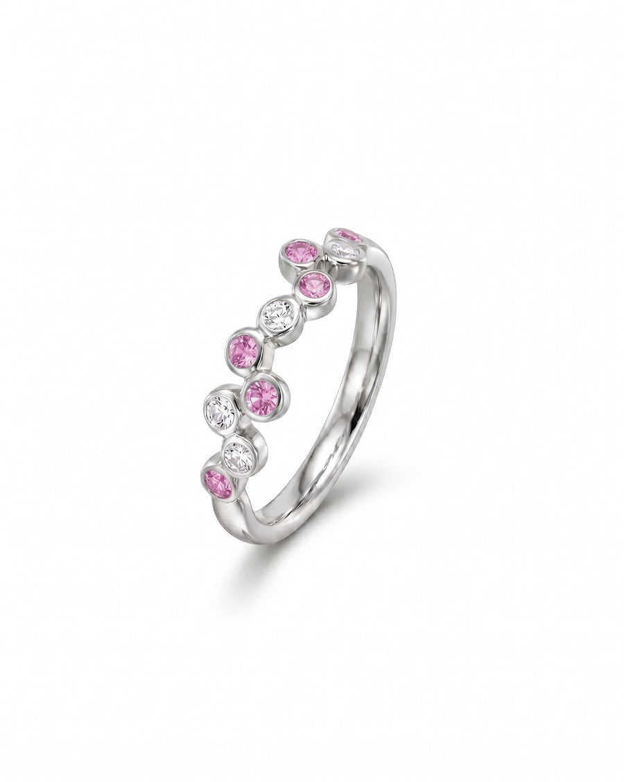 Silver half eternity ring with offset pink and clear round gemstones.