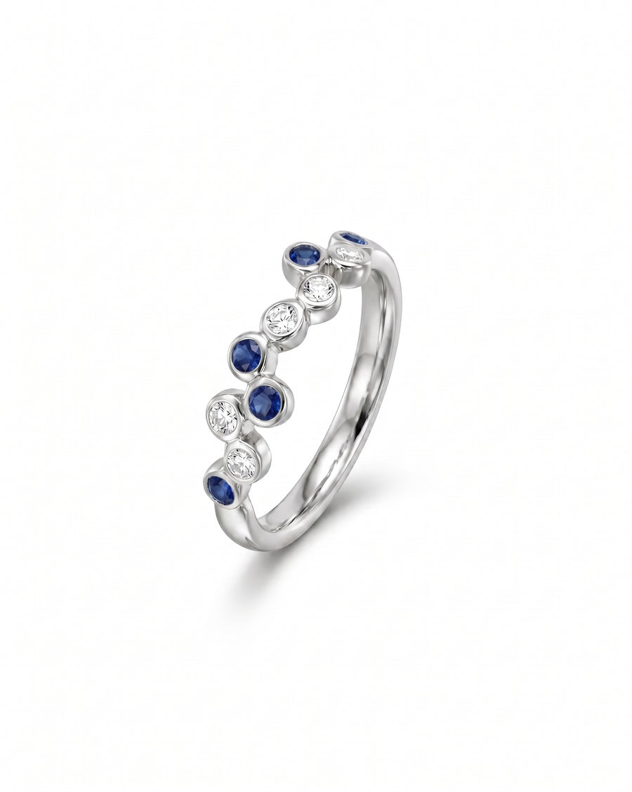 White gold half eternity ring with offset blue sapphires and diamonds.