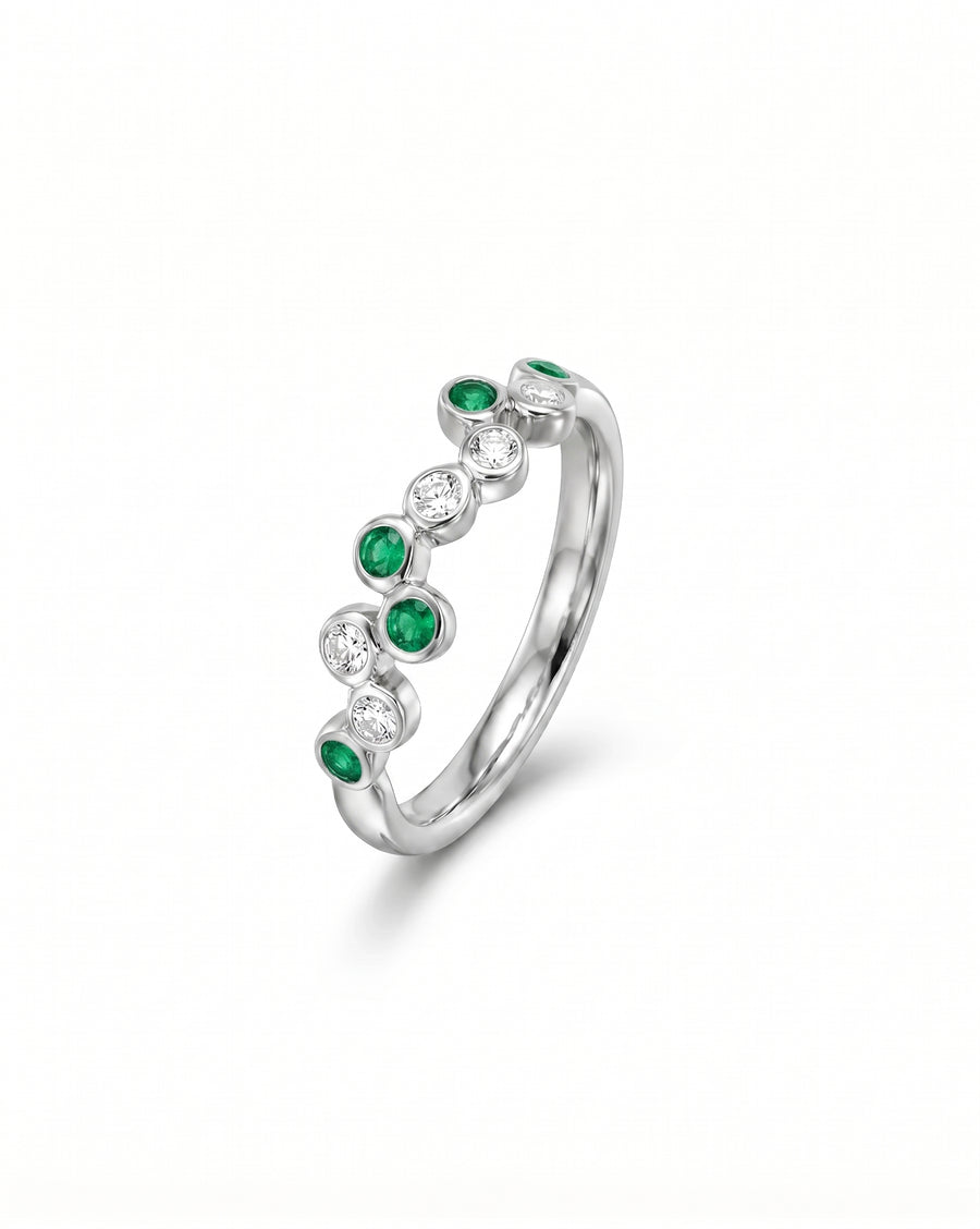 White gold half eternity ring with offset round emeralds and diamonds.