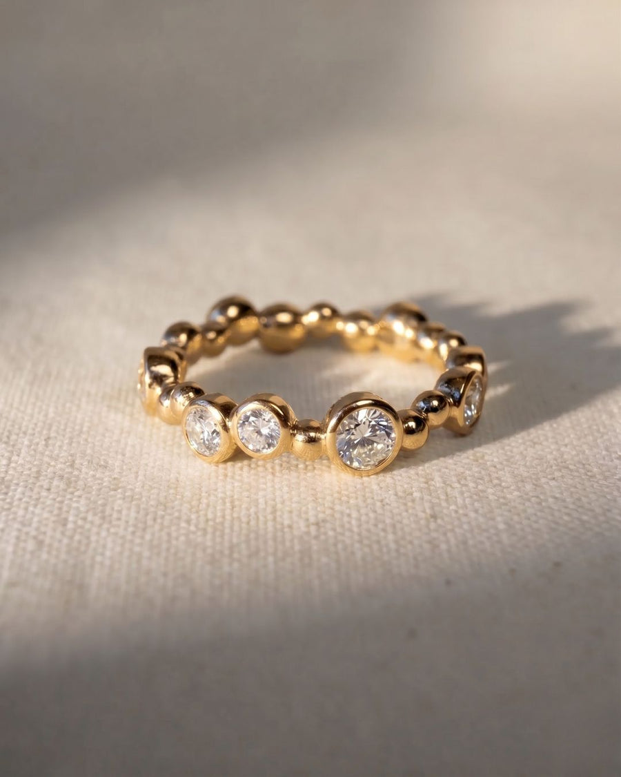 18ct yellow gold eternity ring with random bezel-set diamonds.