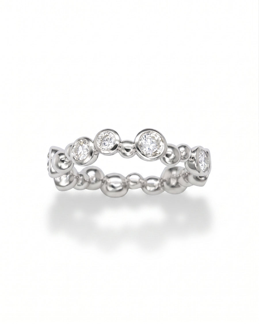 White gold eternity ring with random bezel-set round diamonds and polished bubbles.