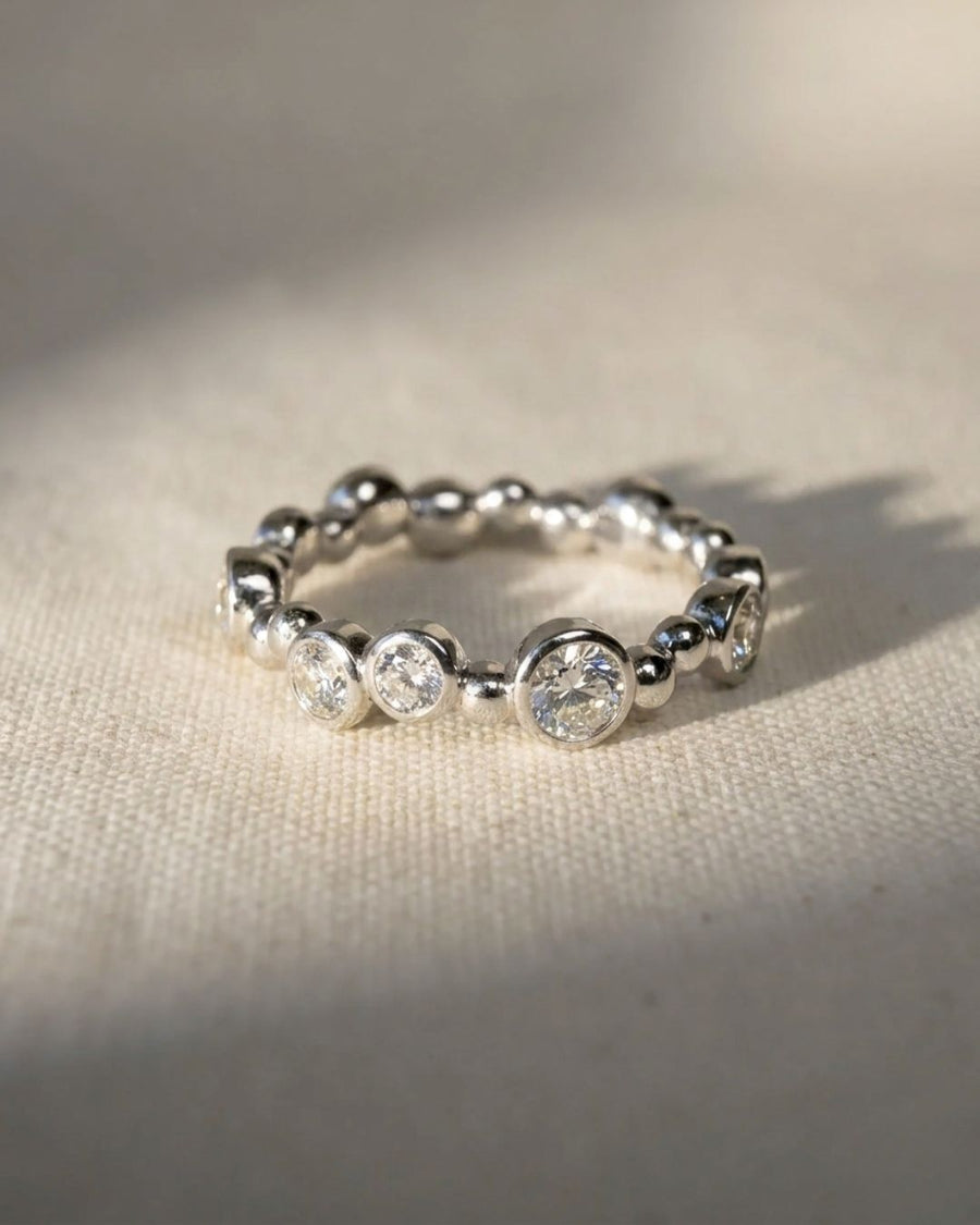 Platinum eternity ring with random bezel-set round diamonds and polished beads.