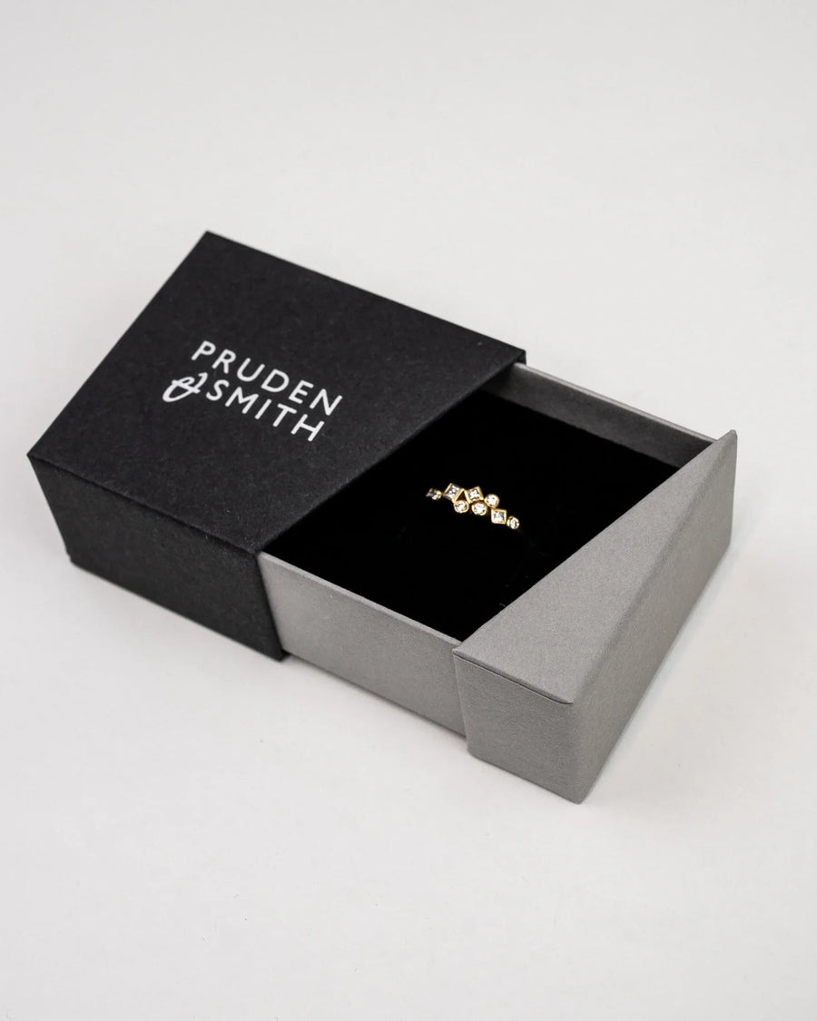 Gold ring with five diamond-shaped gemstones in a black and gray box.