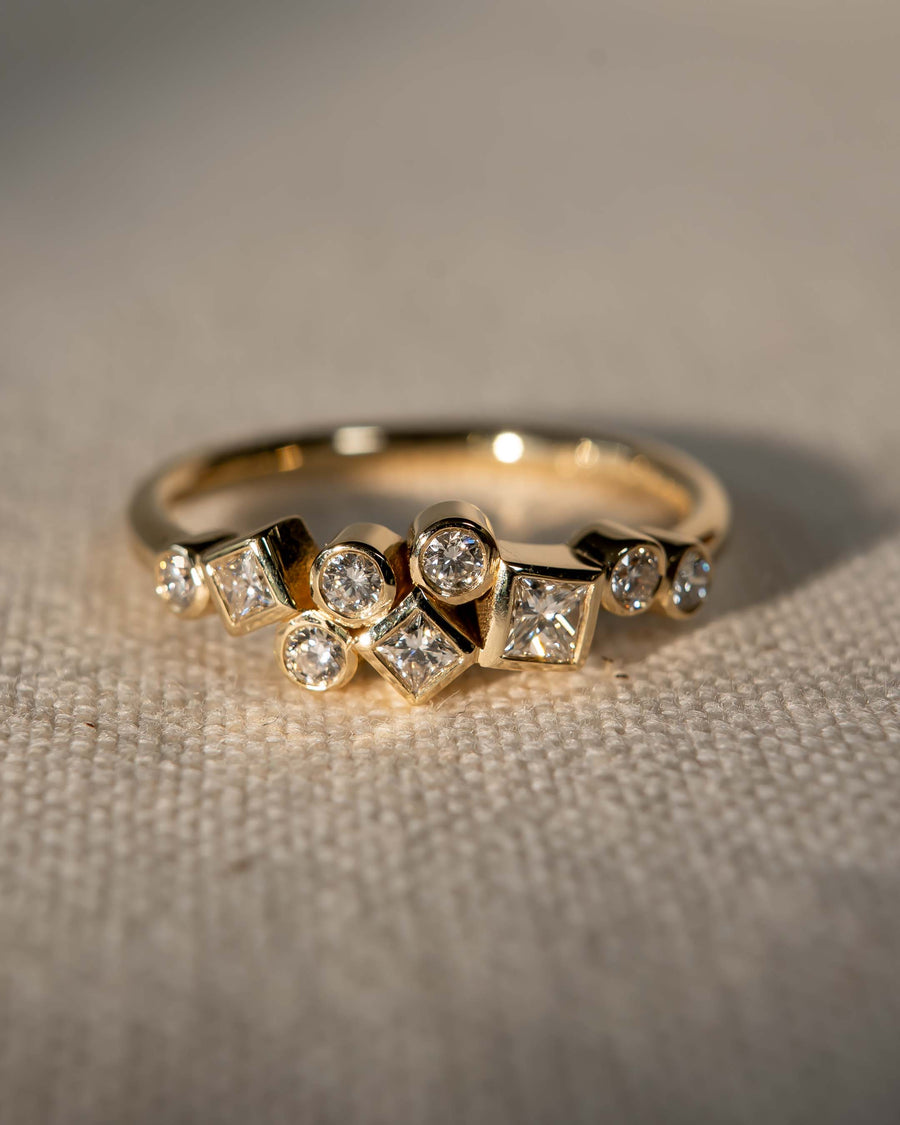 Gold ring with round and square cut diamonds in a cluster design.