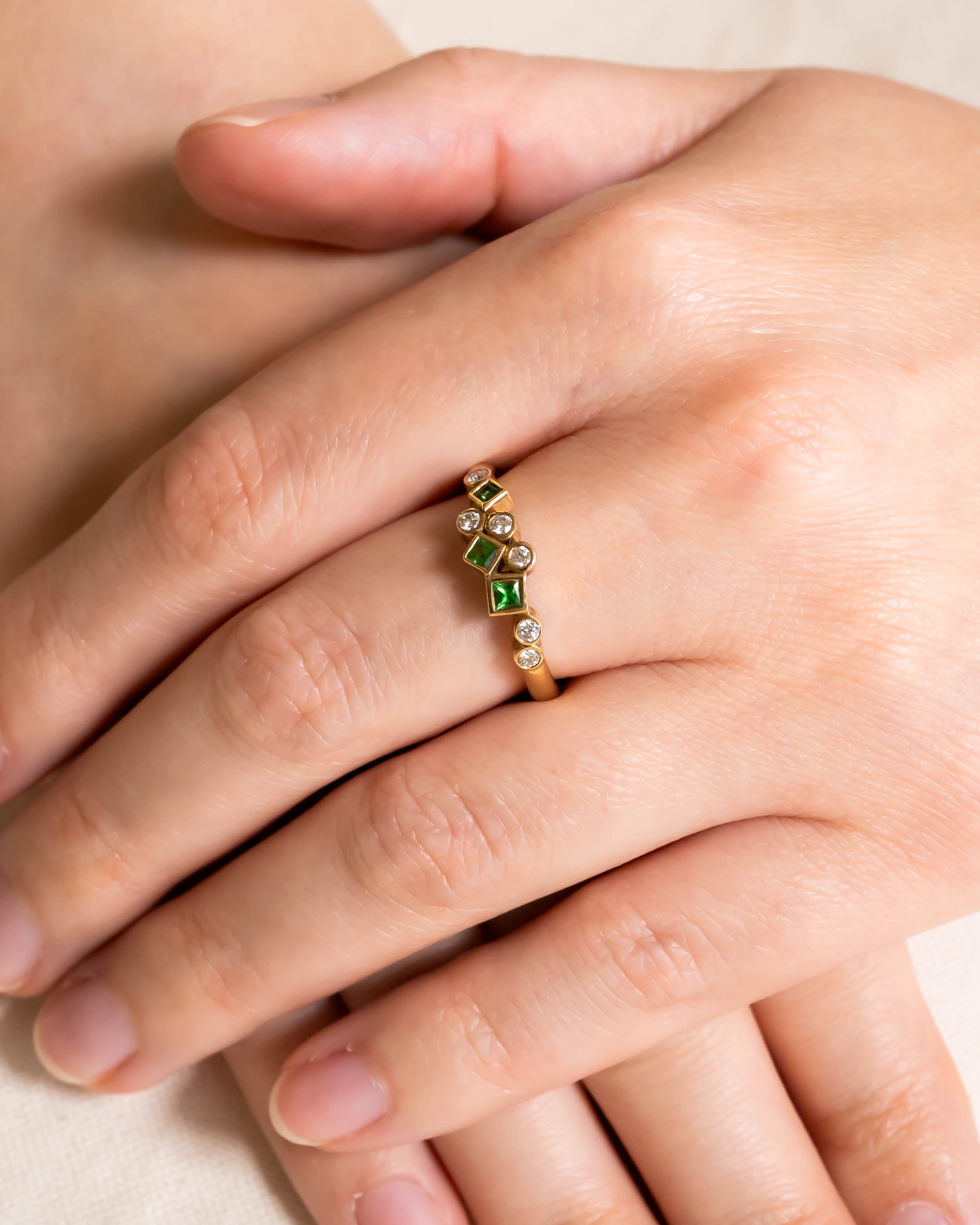 Gold half eternity ring with emerald and diamond gemstones.