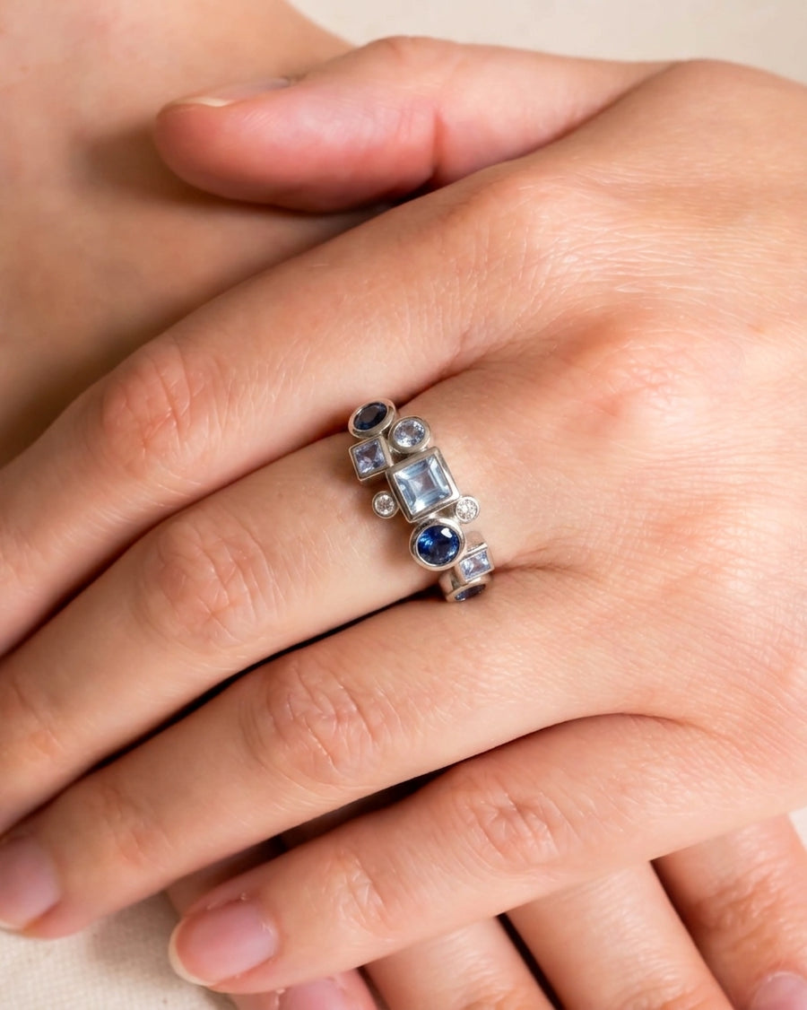 Silver half eternity ring with blue and purple gemstones in varied shapes.