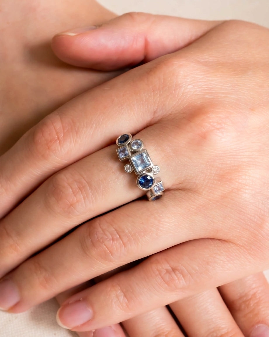 Silver half eternity ring with blue and purple gemstones in varied shapes.