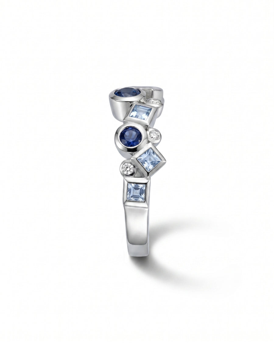 Silver half eternity ring with blue sapphires and diamonds in various shapes.