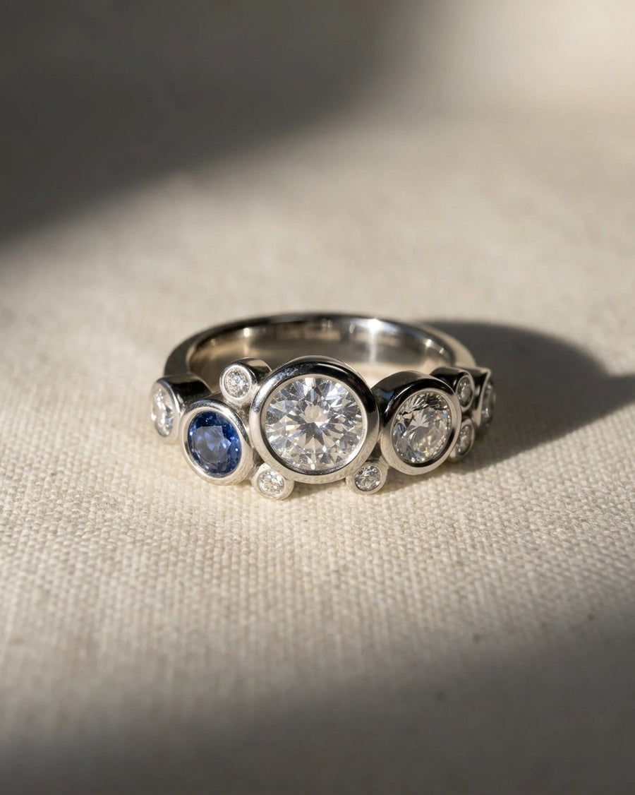 White gold ring with bezel-set sapphire and diamond "bubbles" design.