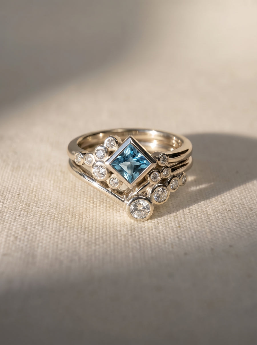 Square aquamarine and diamond ring set in silver metal with a bubble-inspired cluster design.