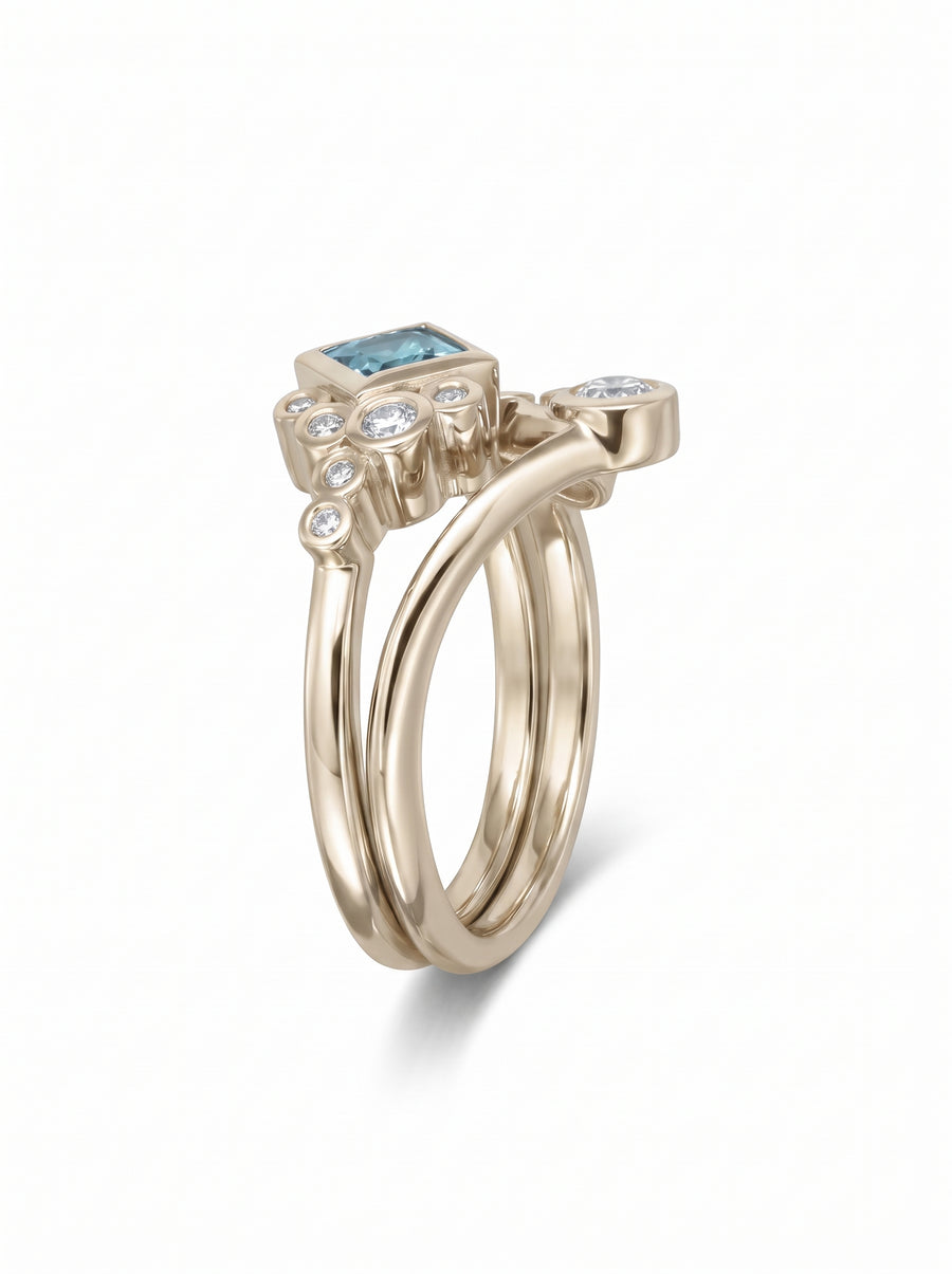 Gold ring set featuring a square aquamarine and small round diamonds in a bubble-style design.