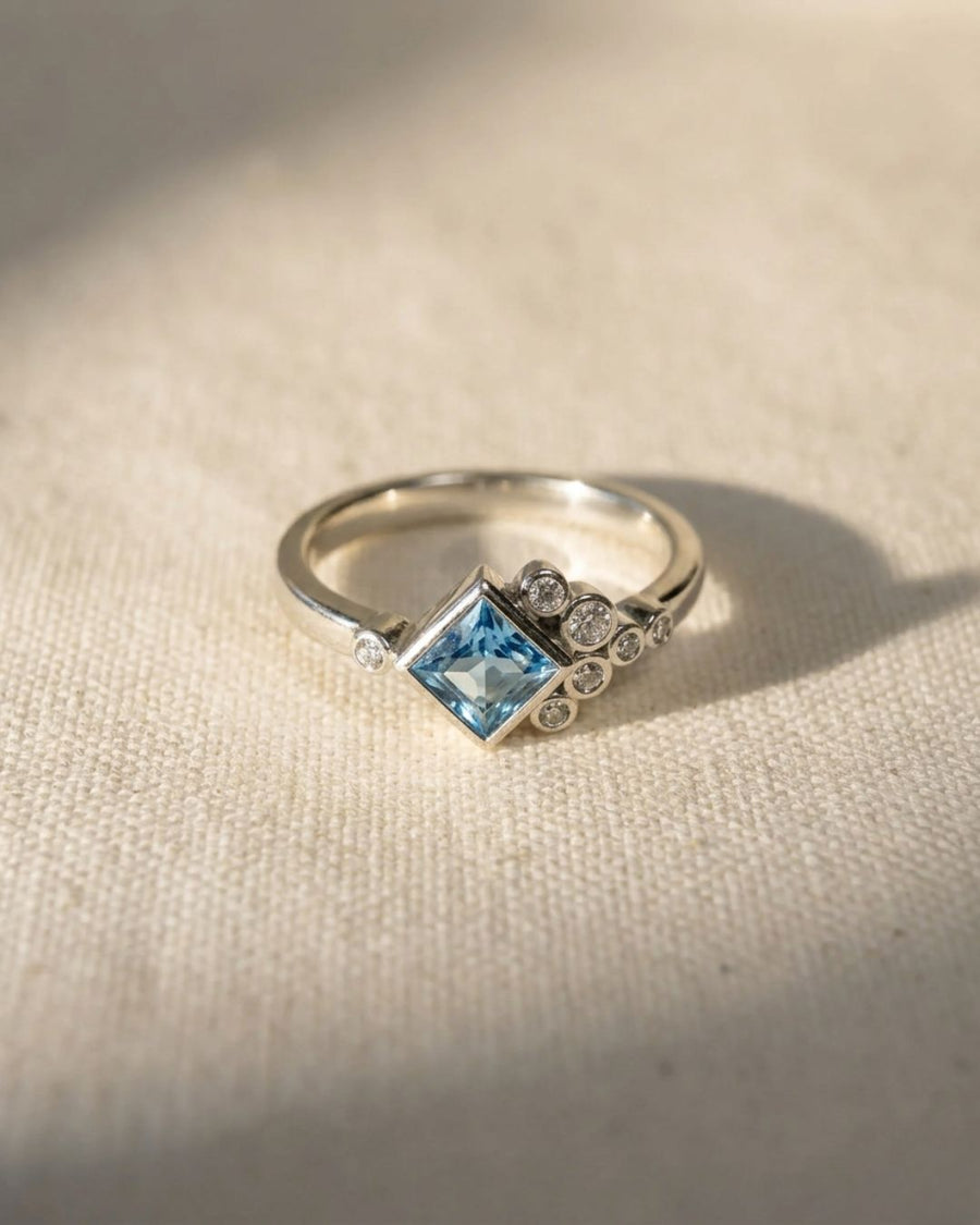 Silver ring with a square aquamarine and round diamonds.