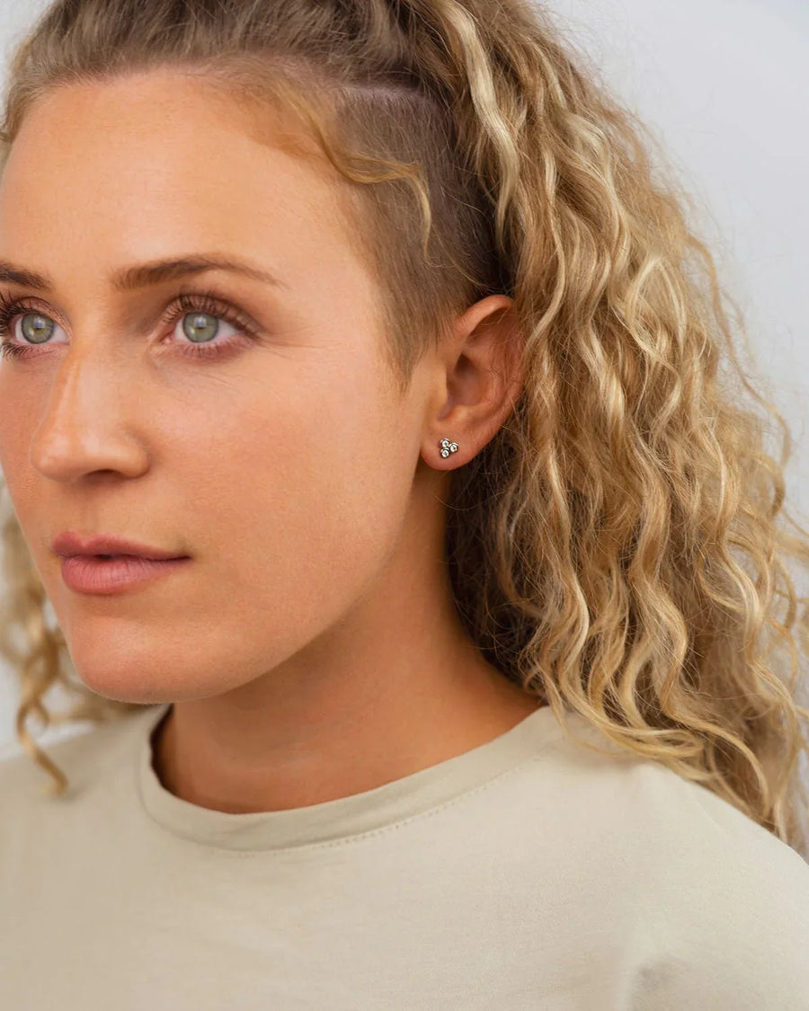 Woman wearing trefoil 9ct yellow gold diamond stud earring, close-up on ear