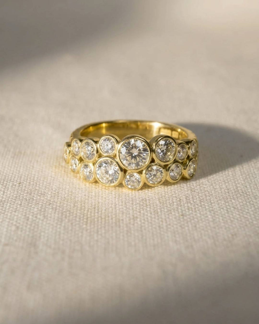 18ct yellow gold two-row diamond ring with various sized bezel-set diamonds.