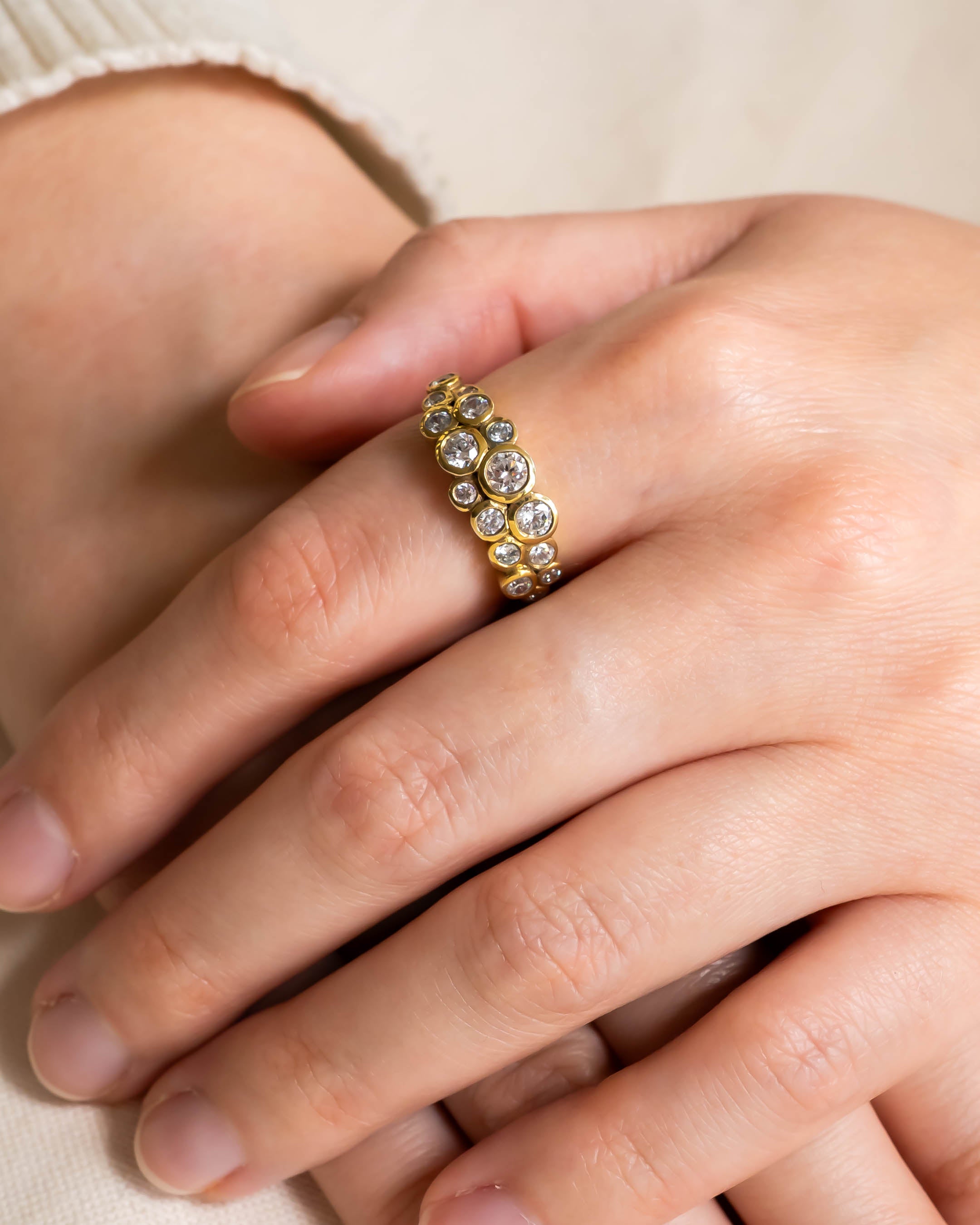 Gold ring with two rows of bezel-set round diamonds on a hand.