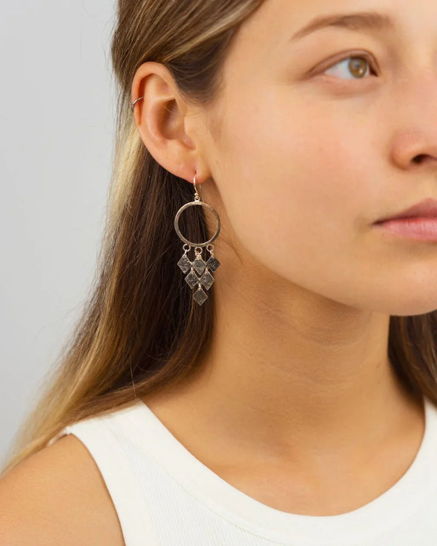 Woman wearing silver chandelier drop earrings with geometric diamond shapes